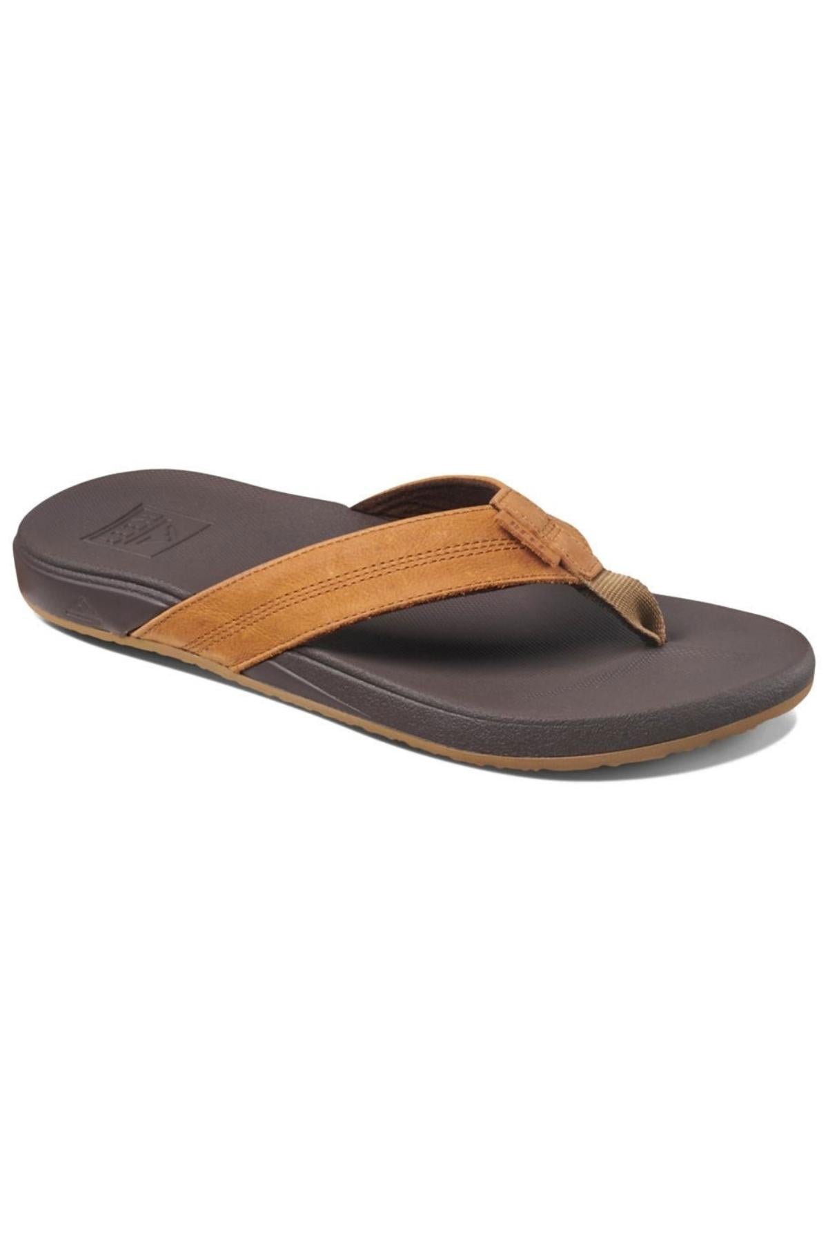 The REEF Cushion Phantom LE is a brown thong sandal with a dark brown sole and tan full grain leather strap, featuring a cushion footbed, shown on a white background.