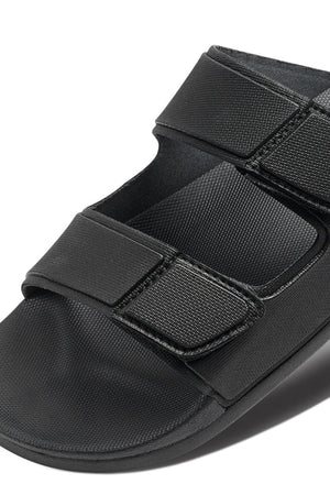 The REEF Cushion Tradewind is a black medical walking sandal with two wide adjustable Velcro straps and a cushioned footbed, designed to support and protect your foot after surgery or injury.