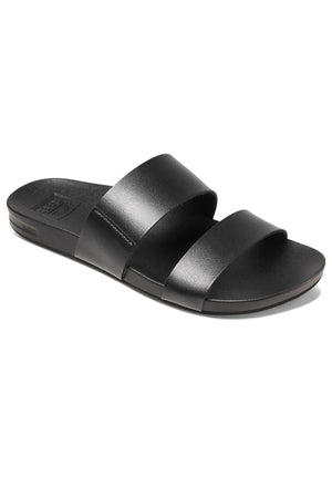 The REEF Cushion Vista sandal features a sleek and minimalistic black design with two wide vegan leather straps across the foot and an open toe. It boasts a flat rubber sole with a cushion bounce midsole for added comfort.