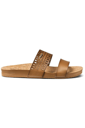 The REEF Cushion Vista Perforated is a brown slide sandal with a cork footbed, arch support, and a slightly elevated sole. It features two straps: one solid at the front and the upper with perforated circular cutouts.