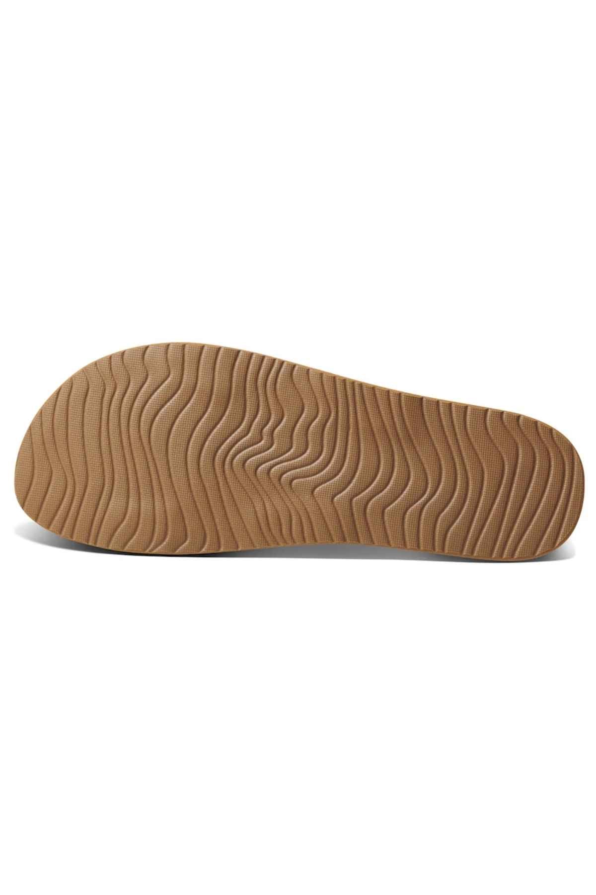 The REEF Cushion Vista sandal showcases a brown sole with a wavy, textured design for grip and arch support against a white backdrop.