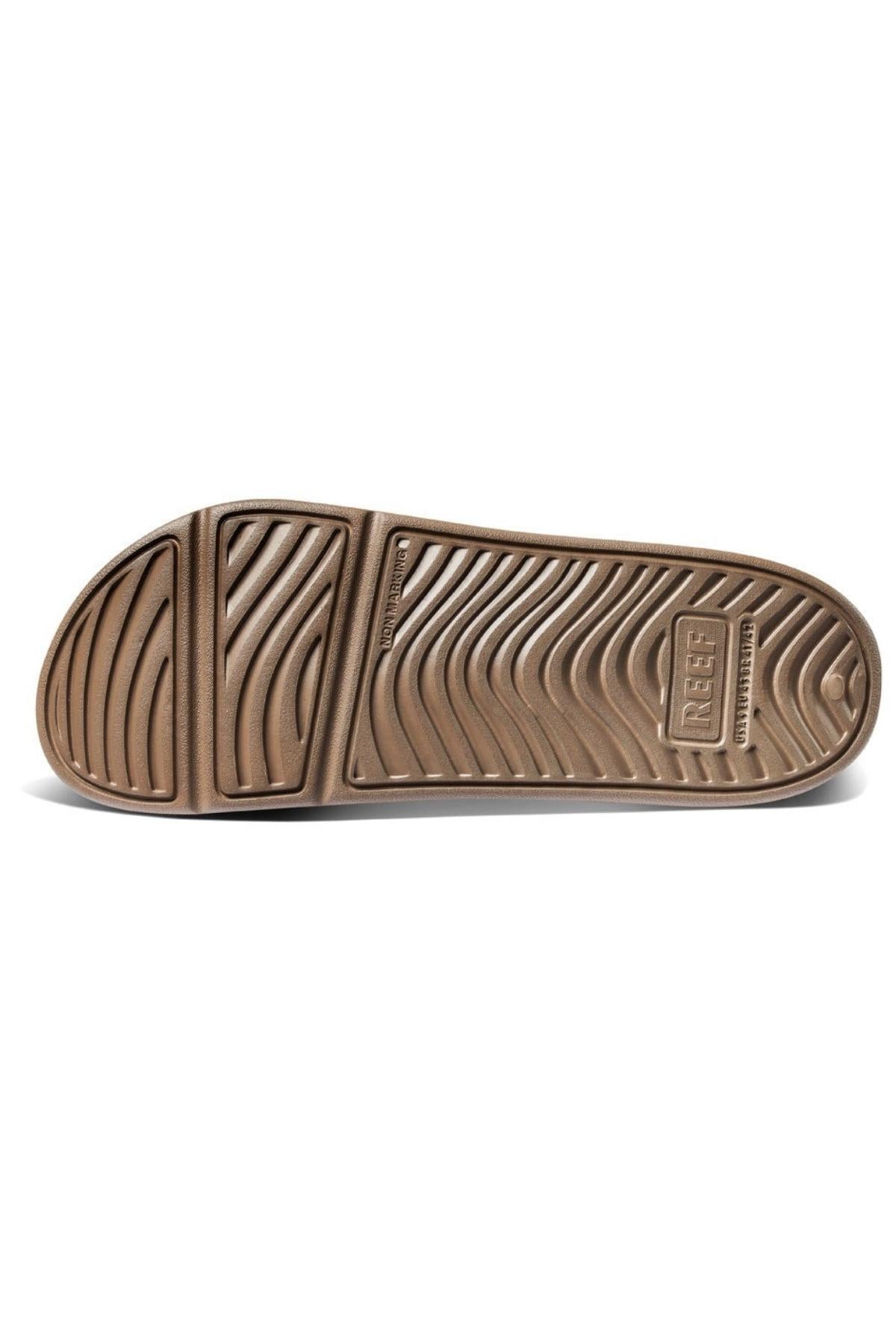 The image shows the sole of the REEF Oasis Double Up sandal, featuring a wavy textured pattern, the "REEF" logo near the heel, built-in arch support, and a renewable sugarcane EVA footbed.