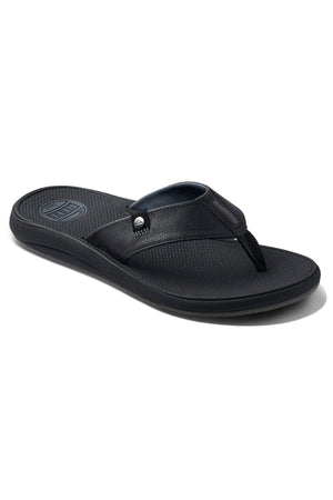 A black flip-flop sandal featuring a textured sole for grip and a durable outsole, with a wide strap across the top of the foot. The strap includes a small metal embellishment and appears to be made of leather, offering both comfort and style akin to the REEF Phantom Nias.