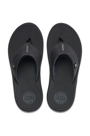 The REEF Phantom Nias flip-flops in black feature a textured footbed and a wide strap over the arch for added comfort. Designed with the brand name "Reef" on both the heel and a small tag on the strap, these comfortable-fit flip-flops boast a simple yet casual look, enhanced by a durable outsole.