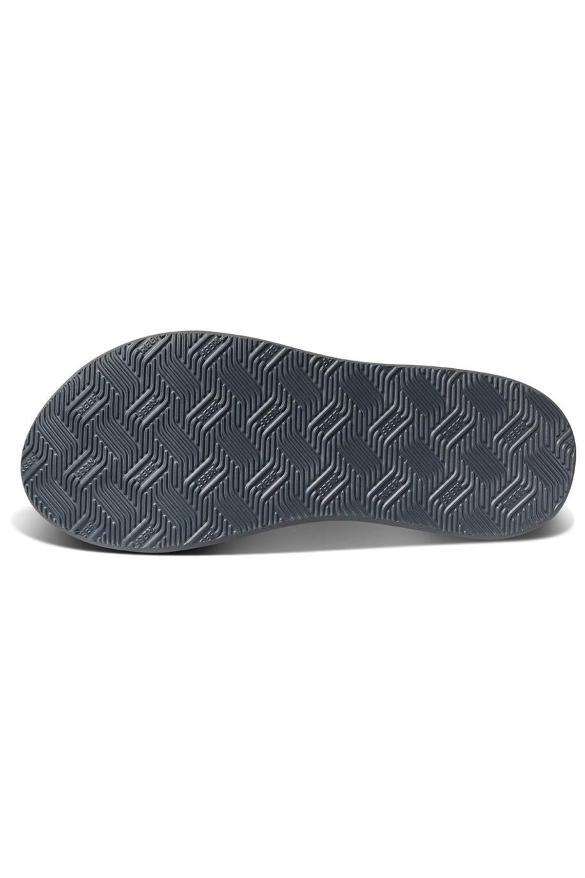 The image depicts the sole of the REEF Phantom Nias shoe. The bottom features a dark gray outsole with a textured pattern of interlocking chevron shapes arranged in a zigzag design, ensuring durability.