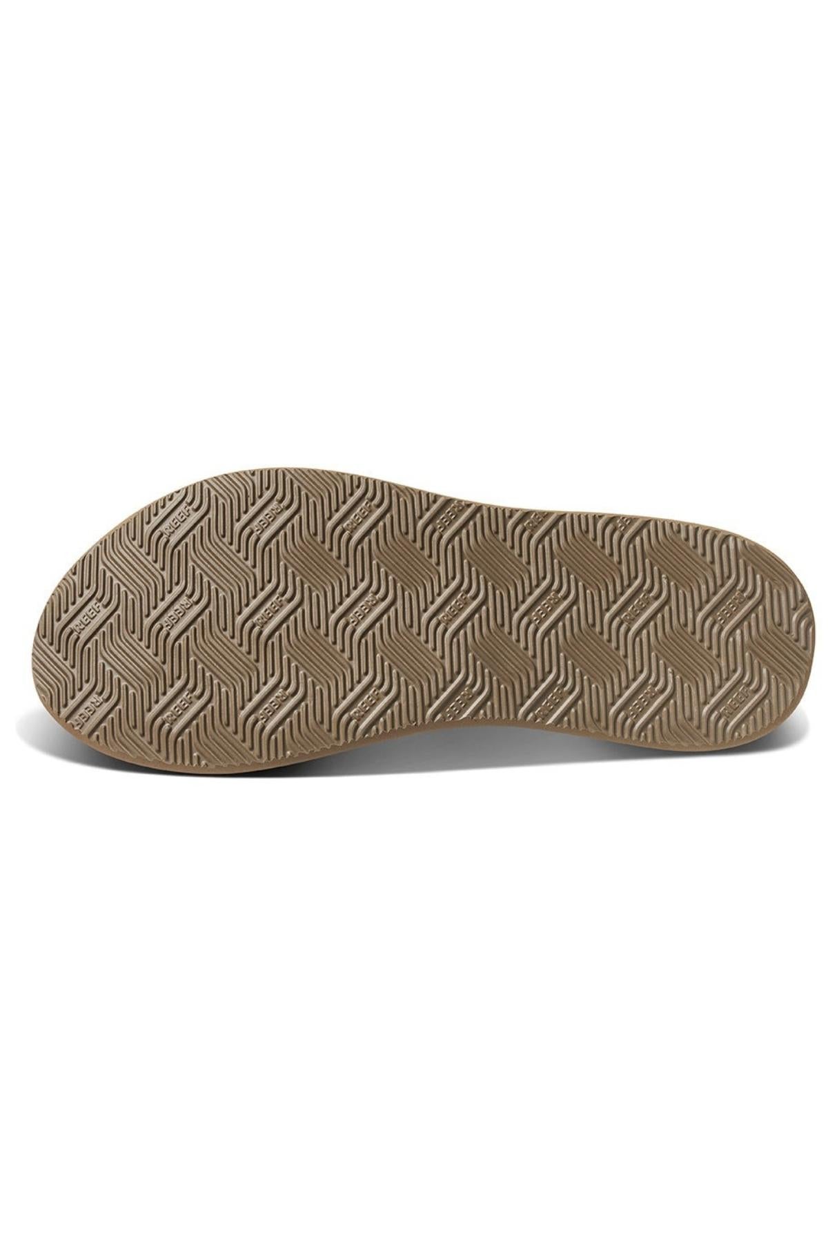 A close-up view of the sole of the REEF Phantom Nias sandal showcases a meticulously patterned design with intricate zigzag lines on durable brown rubber material. Photographed flat against a white background, the image highlights its textured surface and superior traction capabilities.