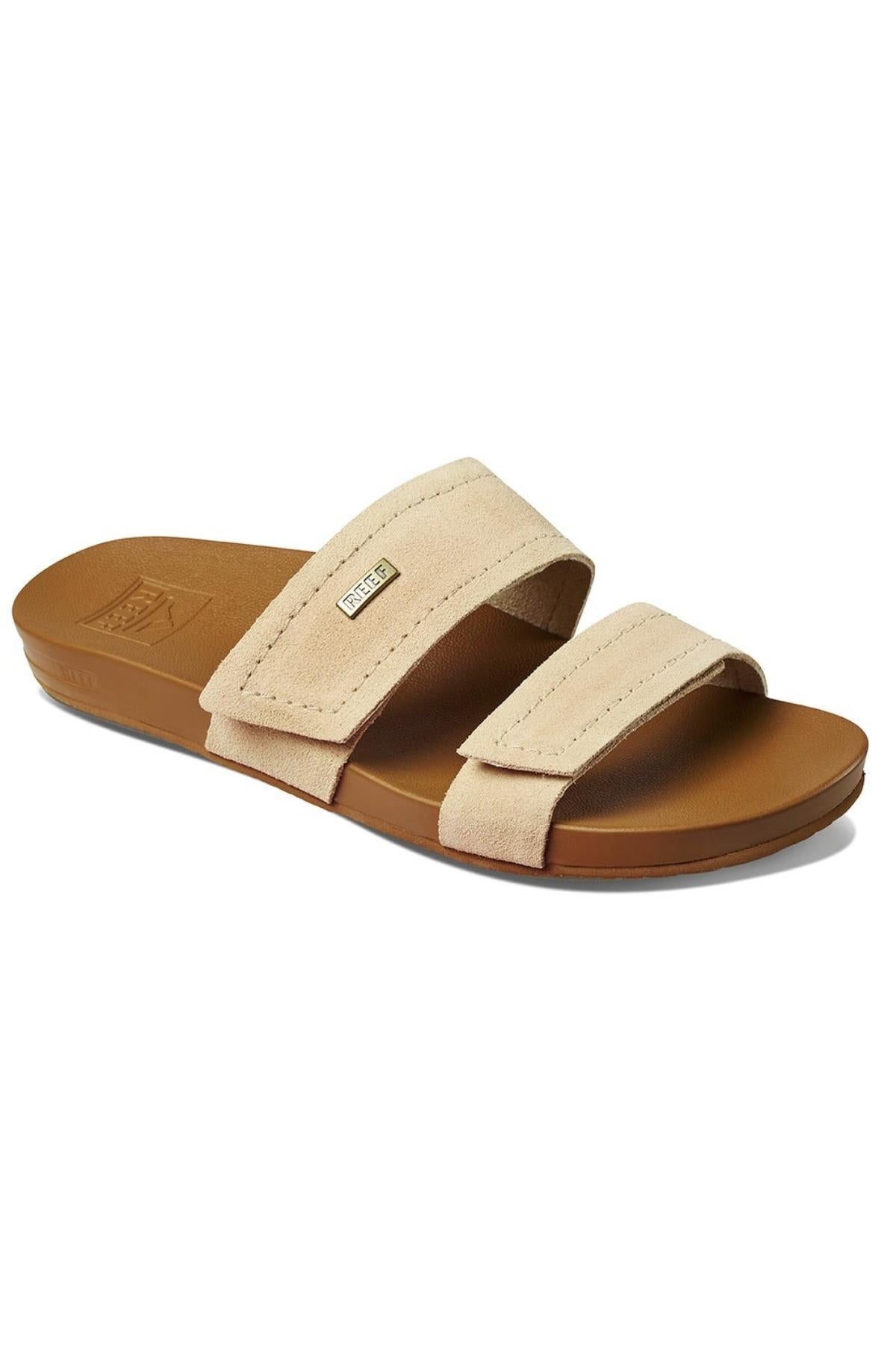 The REEF Velcro Vista SE is a beige slide sandal with cushion bounce midsole, contoured footbed, and premium leather straps featuring stitching details and a small label. It includes a brown rubber sole for added comfort.