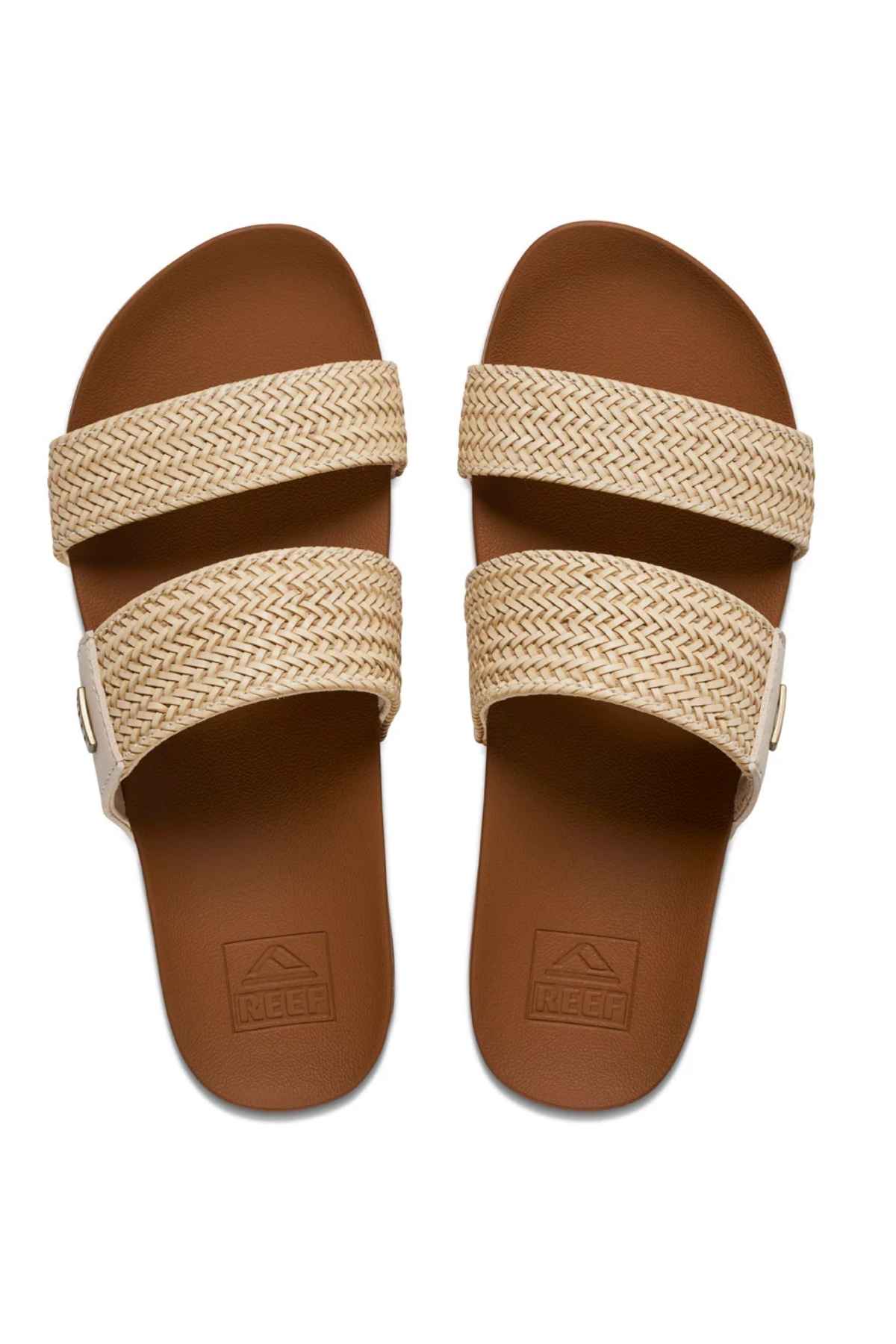 The REEF Vista Braid II slide sandals feature two beige woven straps on each brown sandal, a cushioned midsole for comfort, and an embossed Reef logo on the footbeds.