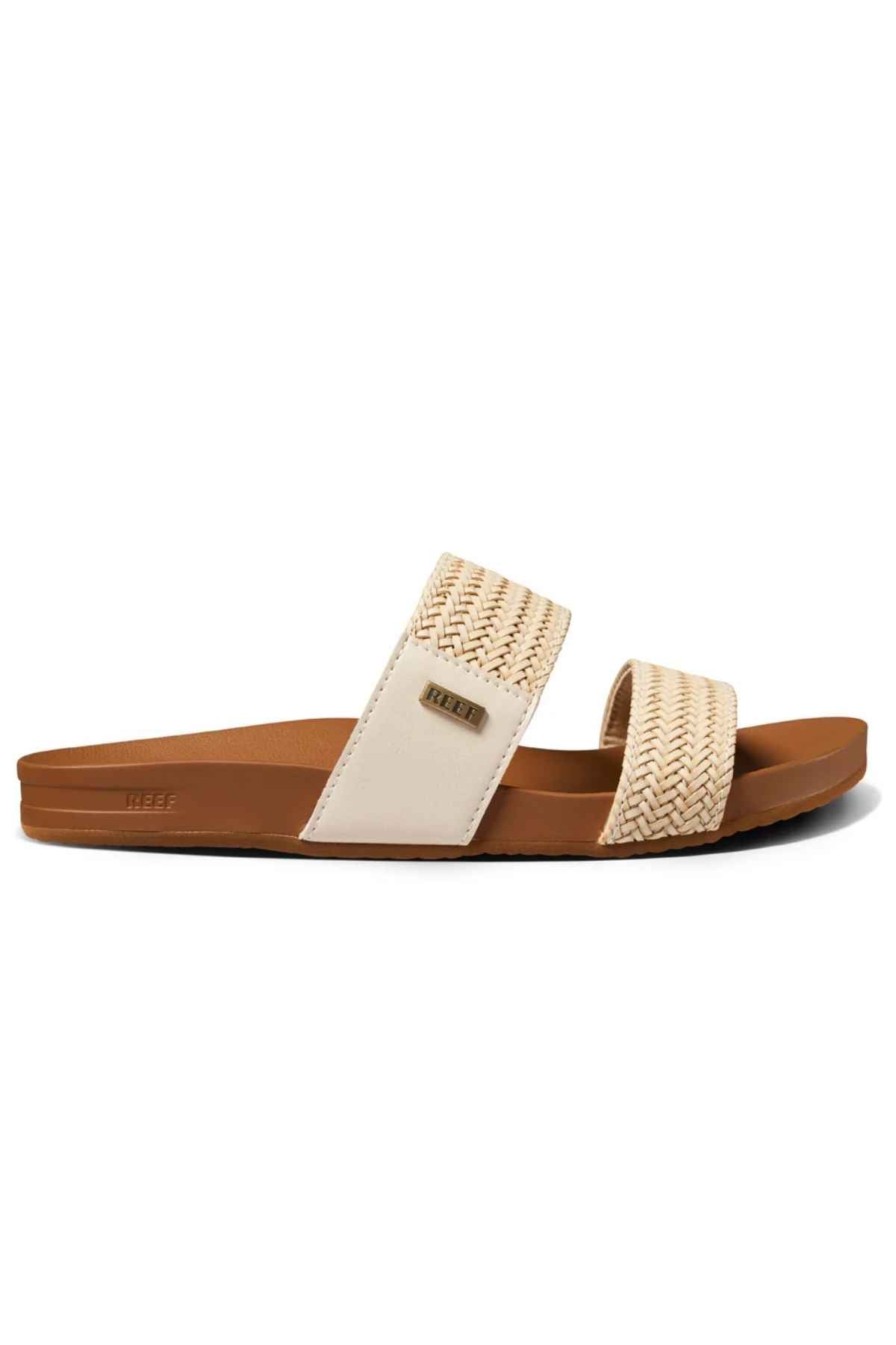 The REEF Vista Braid II is a slide sandal with a flat brown sole, two wide woven beige straps—one featuring a small metallic logo tag—and a cushioned midsole for added comfort.