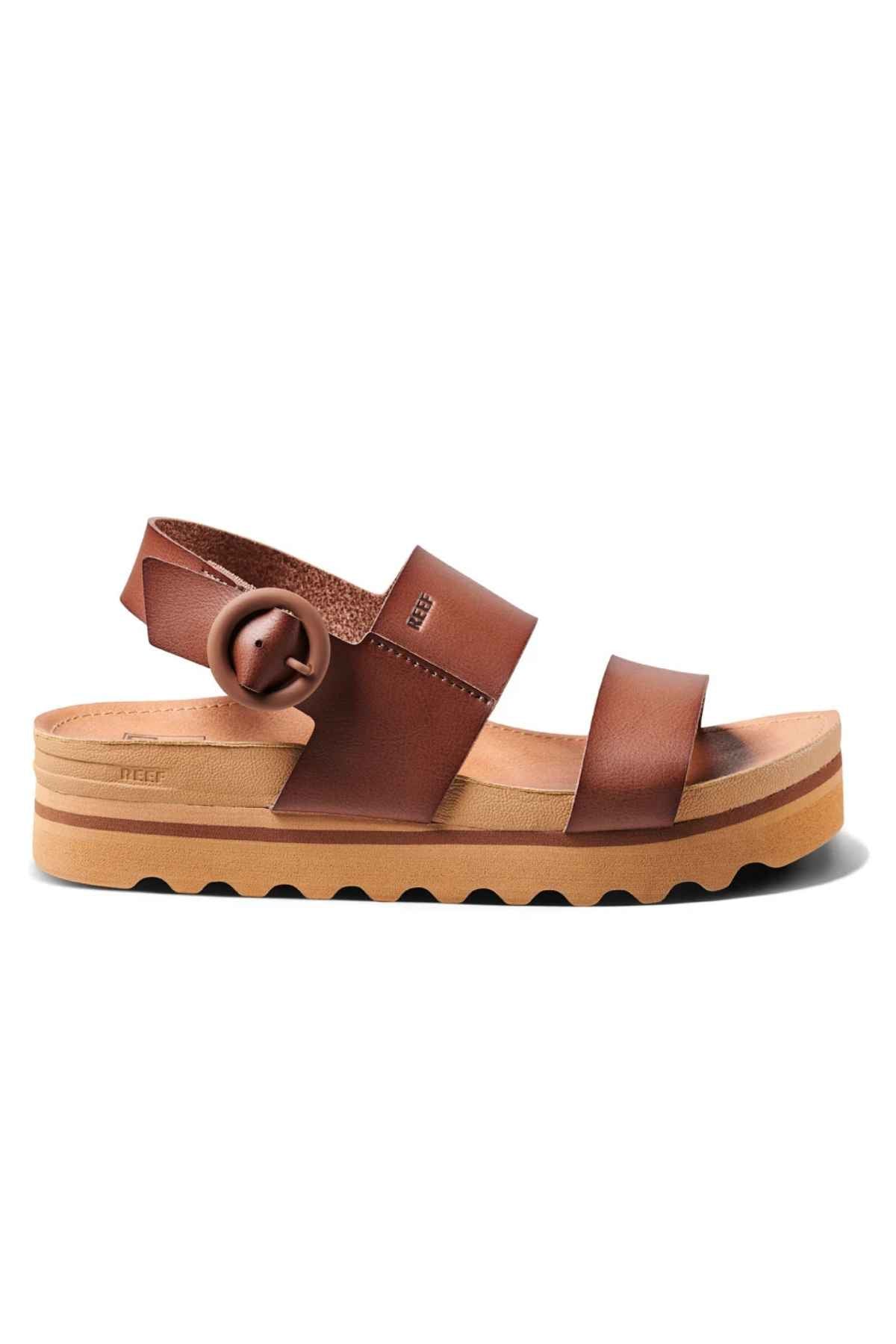 The REEF Vista Hi Buckle sandal showcases straps made from vegan leather and a chunky sole. This platform sandal is designed with a prominent buckle and features a slightly raised platform along with a textured rubber bottom to enhance grip.