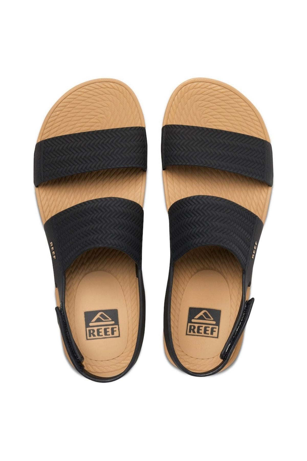 Top view of REEF Water Vista sandals, featuring textured tan soles, two wide black straps providing excellent arch support, and visible brand logos on the insole and strap sides.