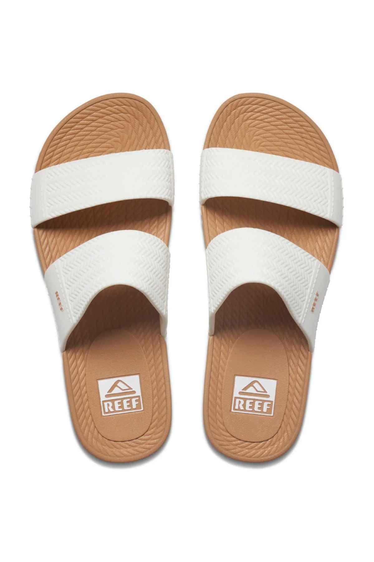 The REEF Water Vista Slide features wide white straps, textured brown soles, and dual-density EVA footbeds with the "REEF" logo. The tan slide sandals are displayed side by side from a top view.