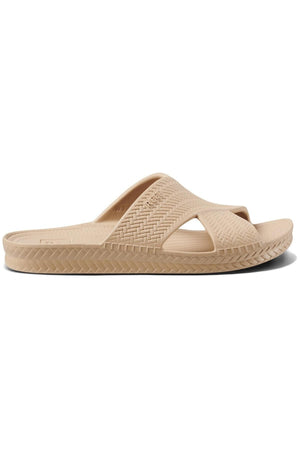 The REEF Water X Slide sandal in beige features a woven texture with a thick cross-foot strap, waterproof EVA straps, and a non-marking sugarcane EVA footbed for comfort and style. A patterned sole border adds elegance.