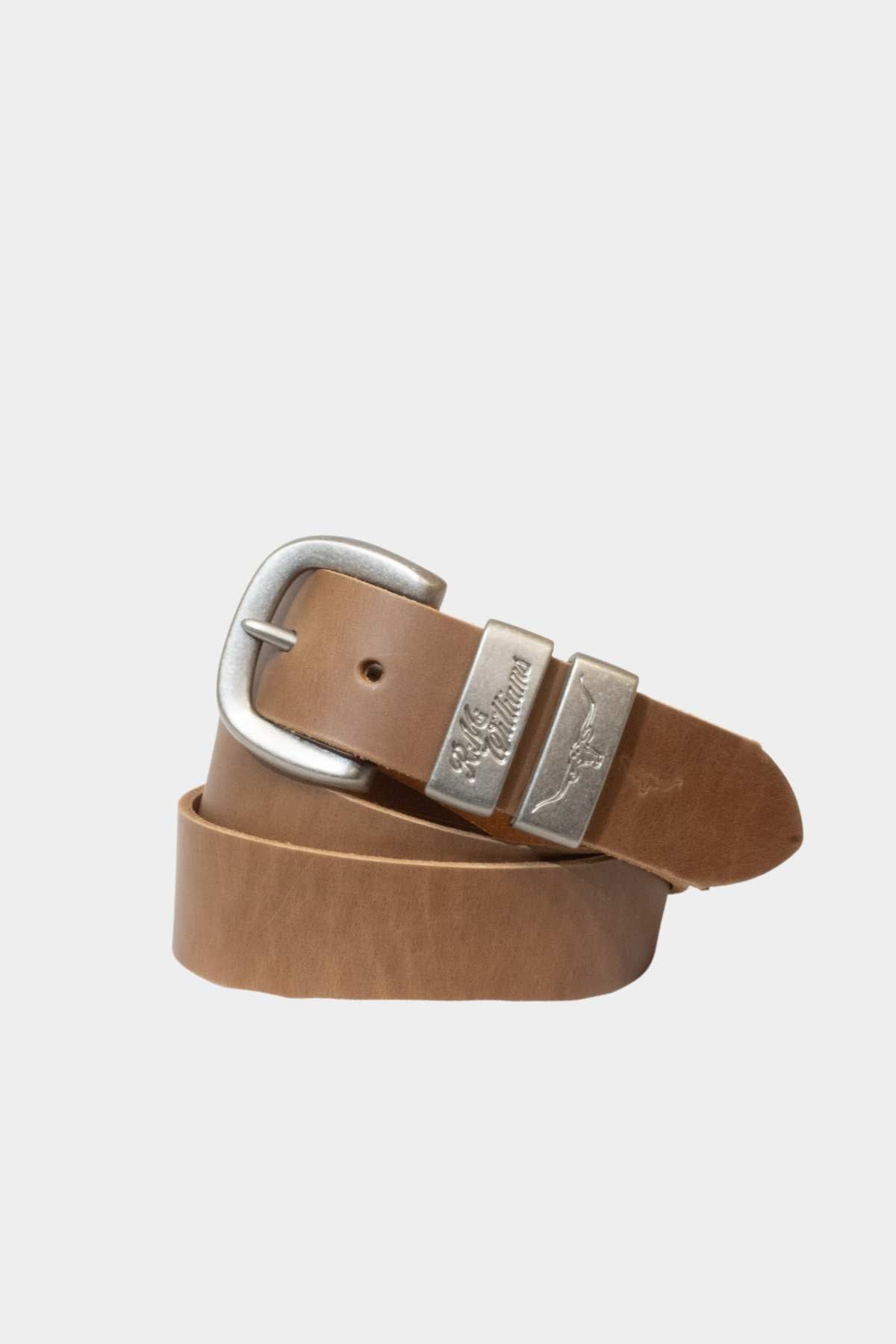 The RM Williams Drover Belt is a tan solid hide leather belt with a brushed nickel rectangular buckle and two silver loops, one engraved with text, shown coiled on a plain light background.