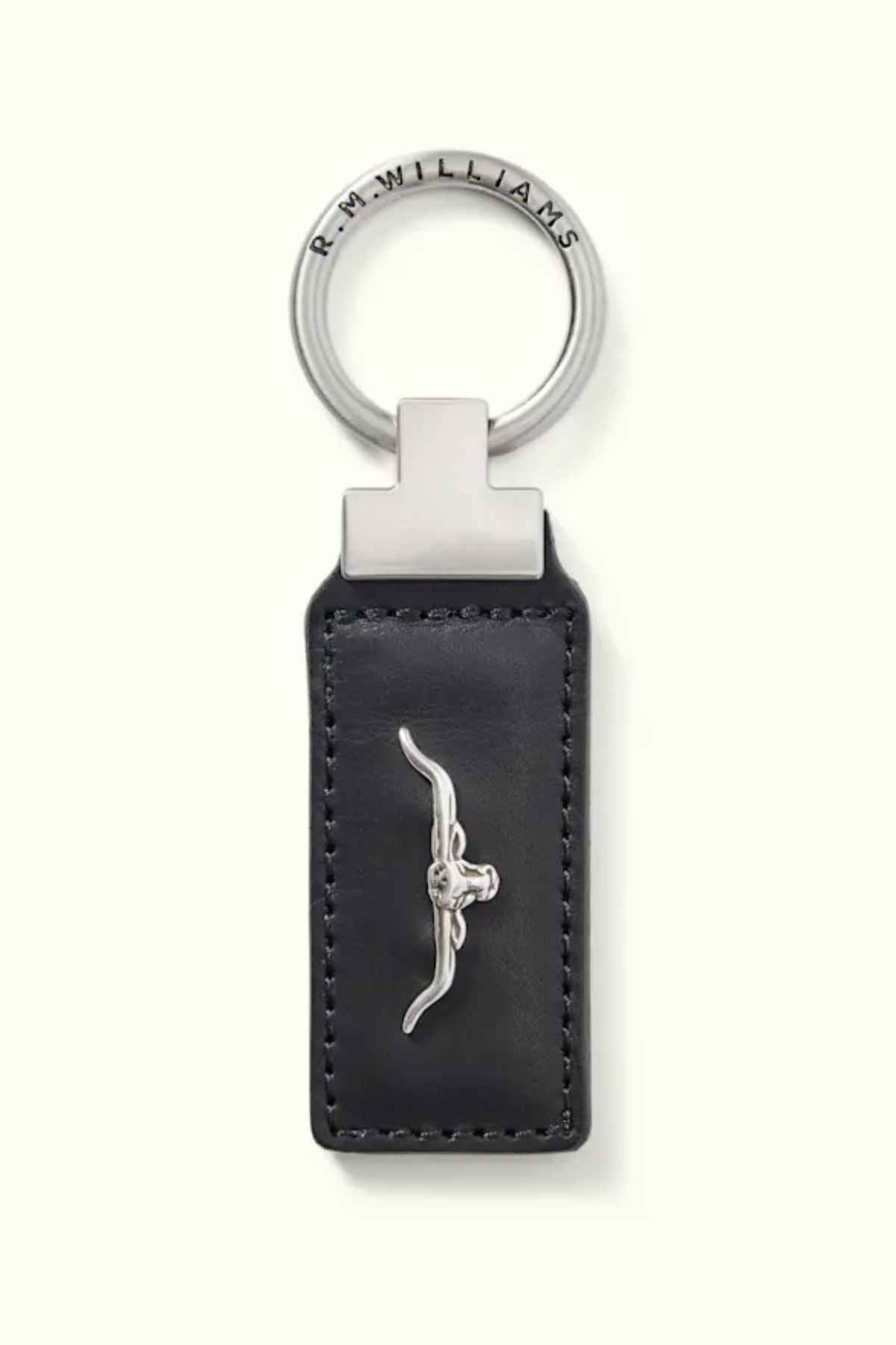 The RM Williams Angaston Key Fob is crafted from black full-grain leather with intricate stitching and showcases a silver metal longhorn emblem at its center. The silver keyring loop is engraved with "R.M. WILLIAMS.