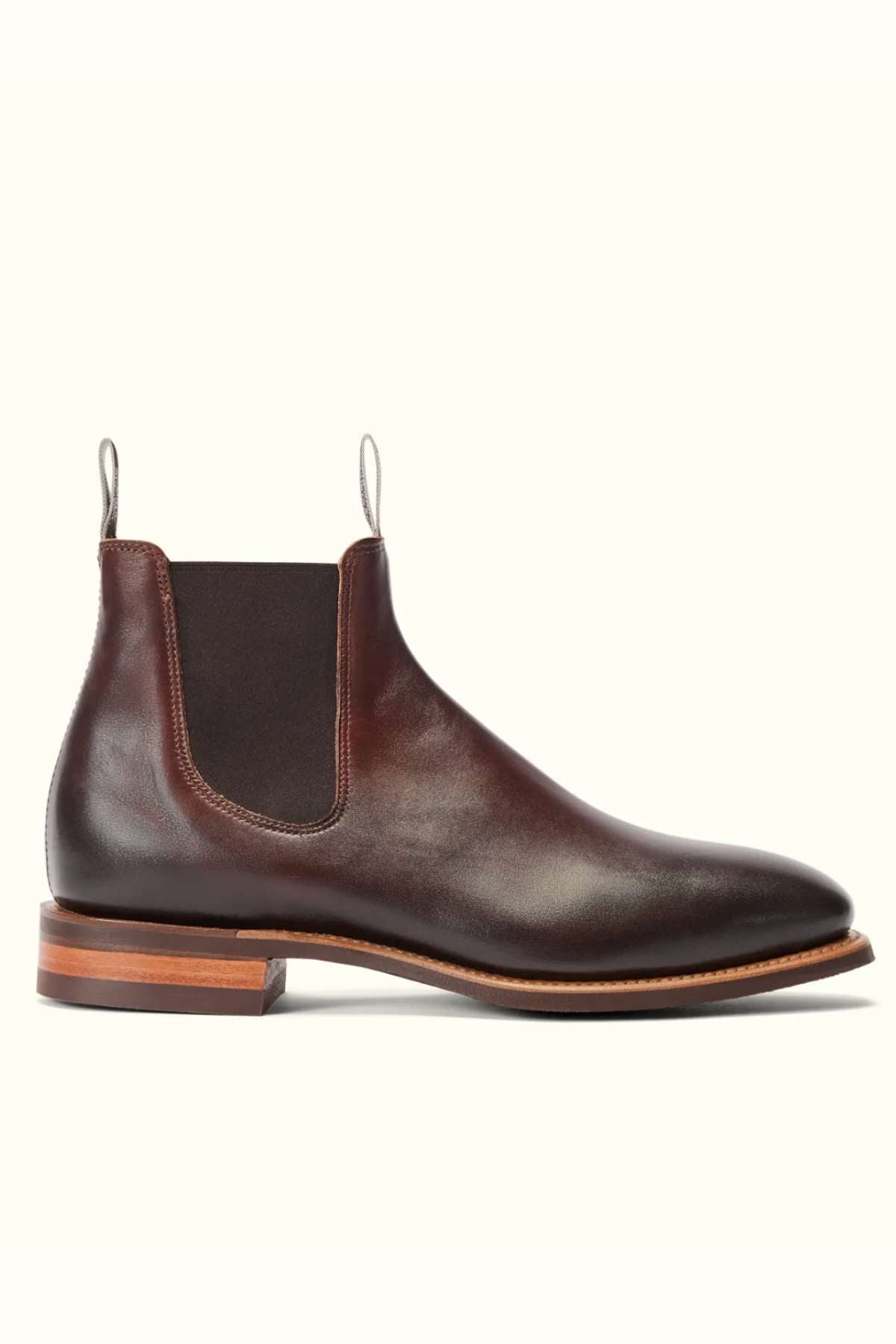 The RM Williams Burnished Comfort Craftsman Boot is a brown burnished leather Chelsea boot with elastic side panels, a heel pull tab, and stacked wooden heel, shown on a white background.
