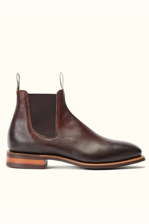 The RM Williams Burnished Comfort Craftsman Boot is a brown burnished leather Chelsea boot with elastic side panels, a heel pull tab, and stacked wooden heel, shown on a white background.