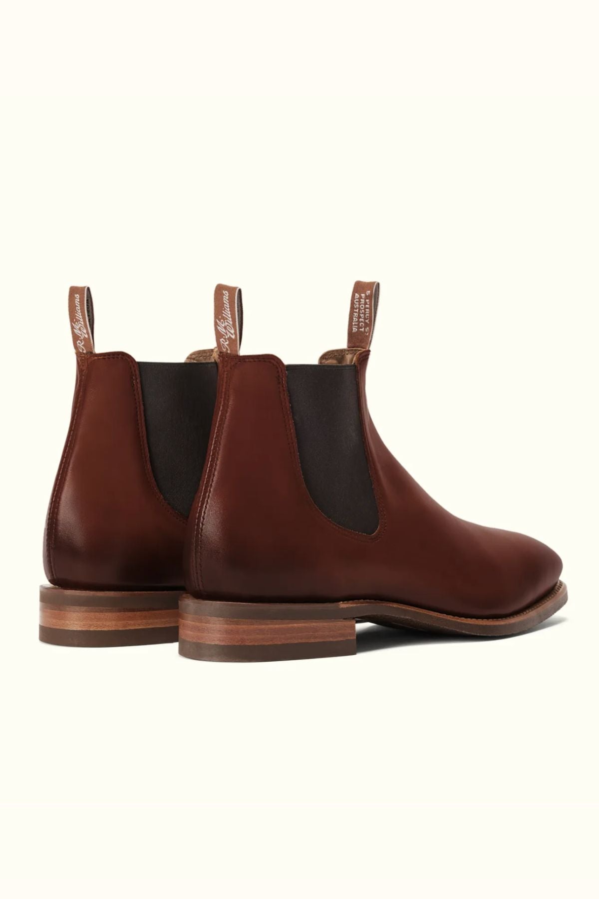 The RM Williams Burnished Comfort Craftsman Boot in brown leather features black elastic side panels and brown pull tabs, displayed from the back and a slight side angle on a neutral background.