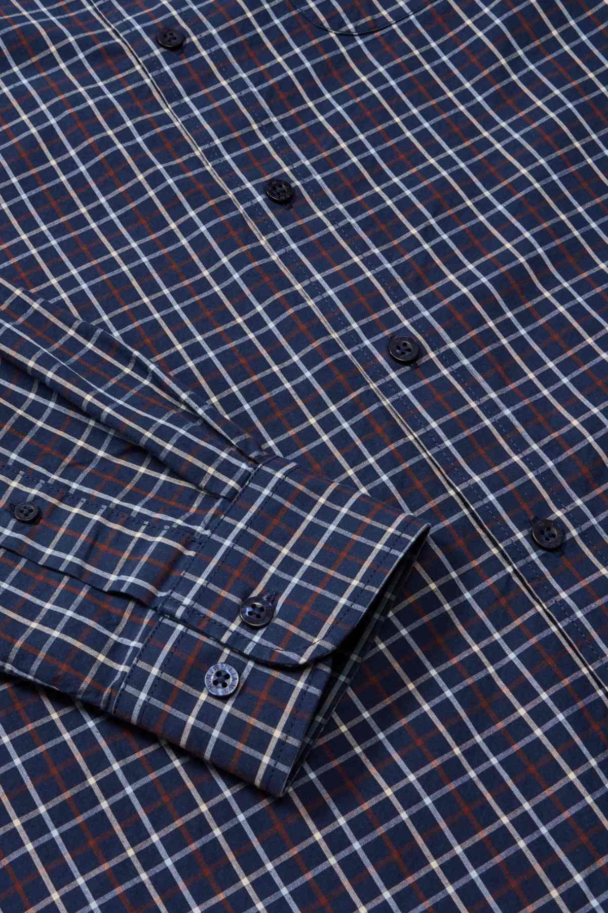A close-up view of the RM Williams Classic Shirt, a blue and red checkered long-sleeve regular fit shirt, featuring dark blue buttons and a neatly folded sleeve. Made from organic cotton, the pattern consists of intersecting lines forming squares, perfect for a smart casual look.