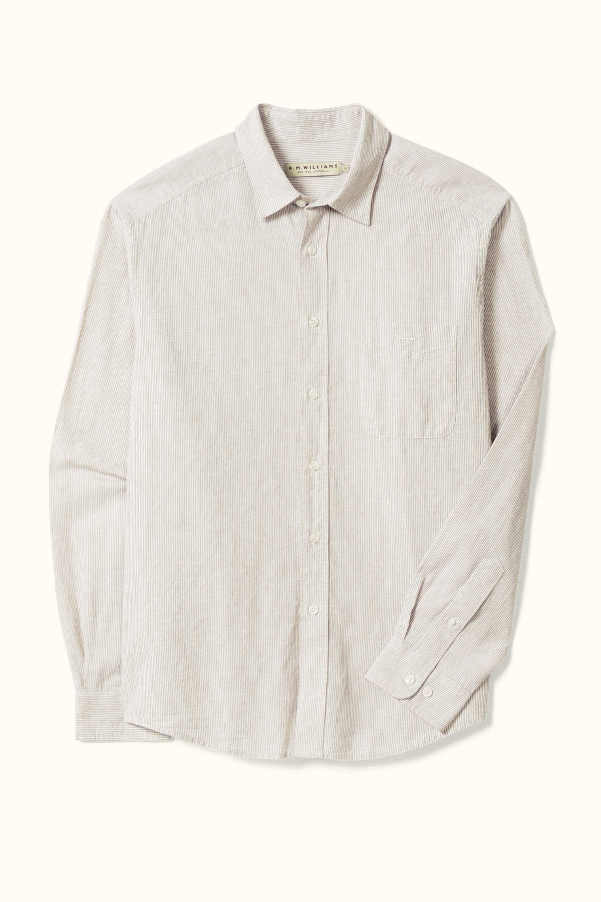 This RM Williams Classic Shirt in light beige showcases a subtle vertical stripe pattern. Crafted from a striped cotton linen blend, it features an embroidered longhorn on the chest pocket and buttoned cuffs, all set against a plain background.