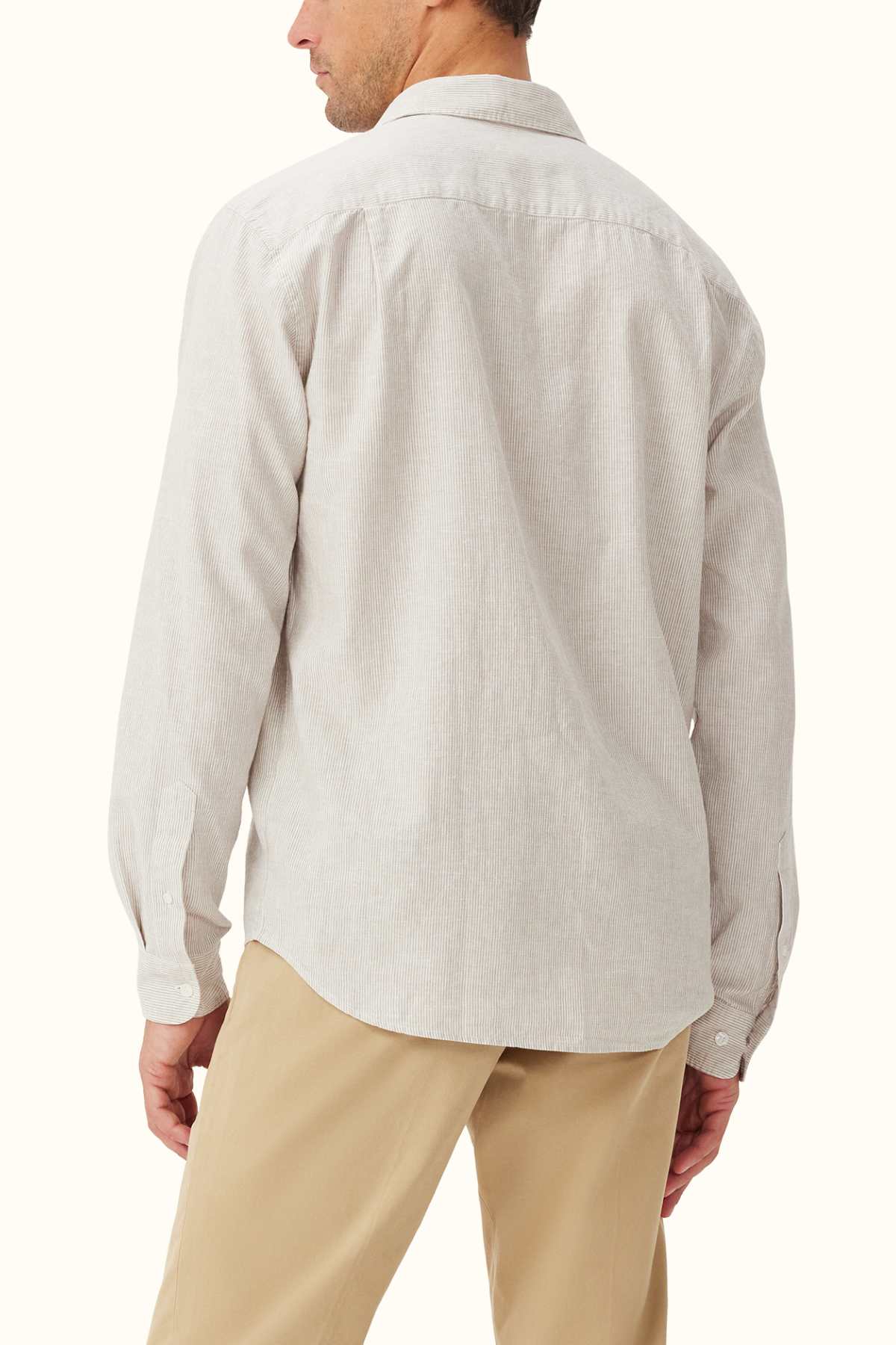 A person clad in a light gray RM Williams Classic Shirt, crafted from a striped cotton linen blend, and beige pants stands facing away, showcasing the back of the outfit.