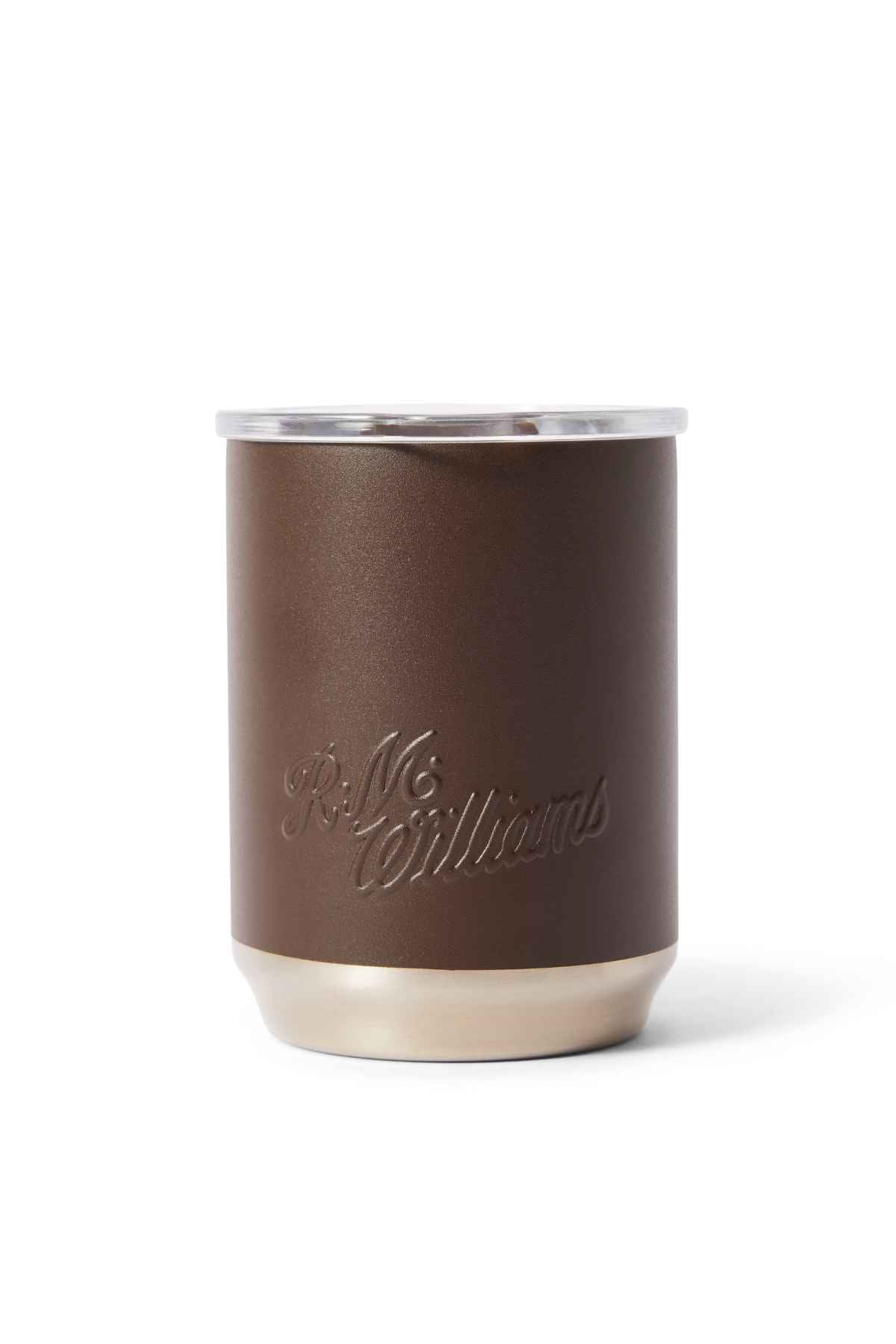 A small brown RM Williams Coffee Cup features a minimalist design with a silver base and rim, embossed "R.M. Williams" text on its side. Made of stainless steel, it combines style with sustainability.