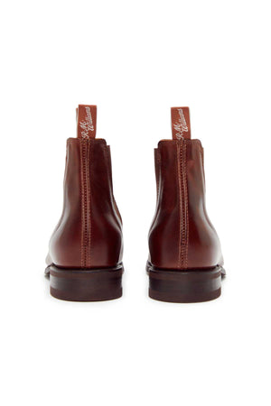 The RM Williams Comfort Craftsman Boot in brown yearling leather is shown from the back, featuring pull tabs with white script, low stacked heels, and a durable rubber welt sole.