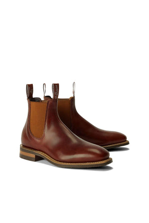 The RM Williams Comfort Craftsman Boot is a pair of brown leather Chelsea boots featuring tan elastic side panels, pull tabs, and wooden heels, shown on a white background.
