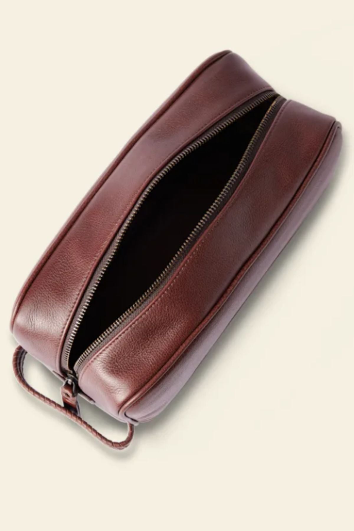 The RM Williams Farrier Signature Washbag in brown tumbled grain leather features a small handle, rounded edges, water-resistant lining, and a zippered opening revealing its spacious interior. Displayed on a light background.