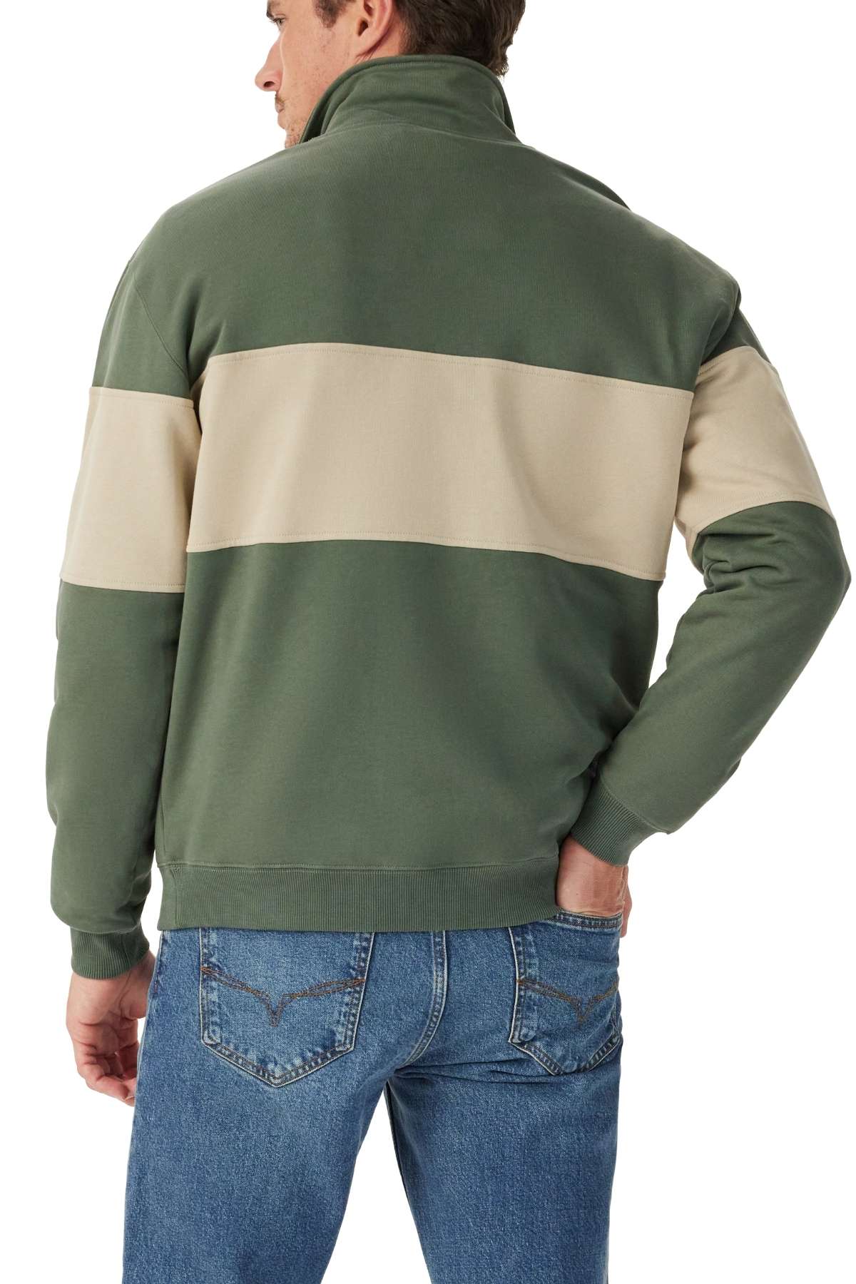 A man seen from behind, wearing blue jeans and an RM Williams Heritage 1/4 Zip Sweatshirt with a wide beige stripe across the back and sleeves, has one hand in his pocket.