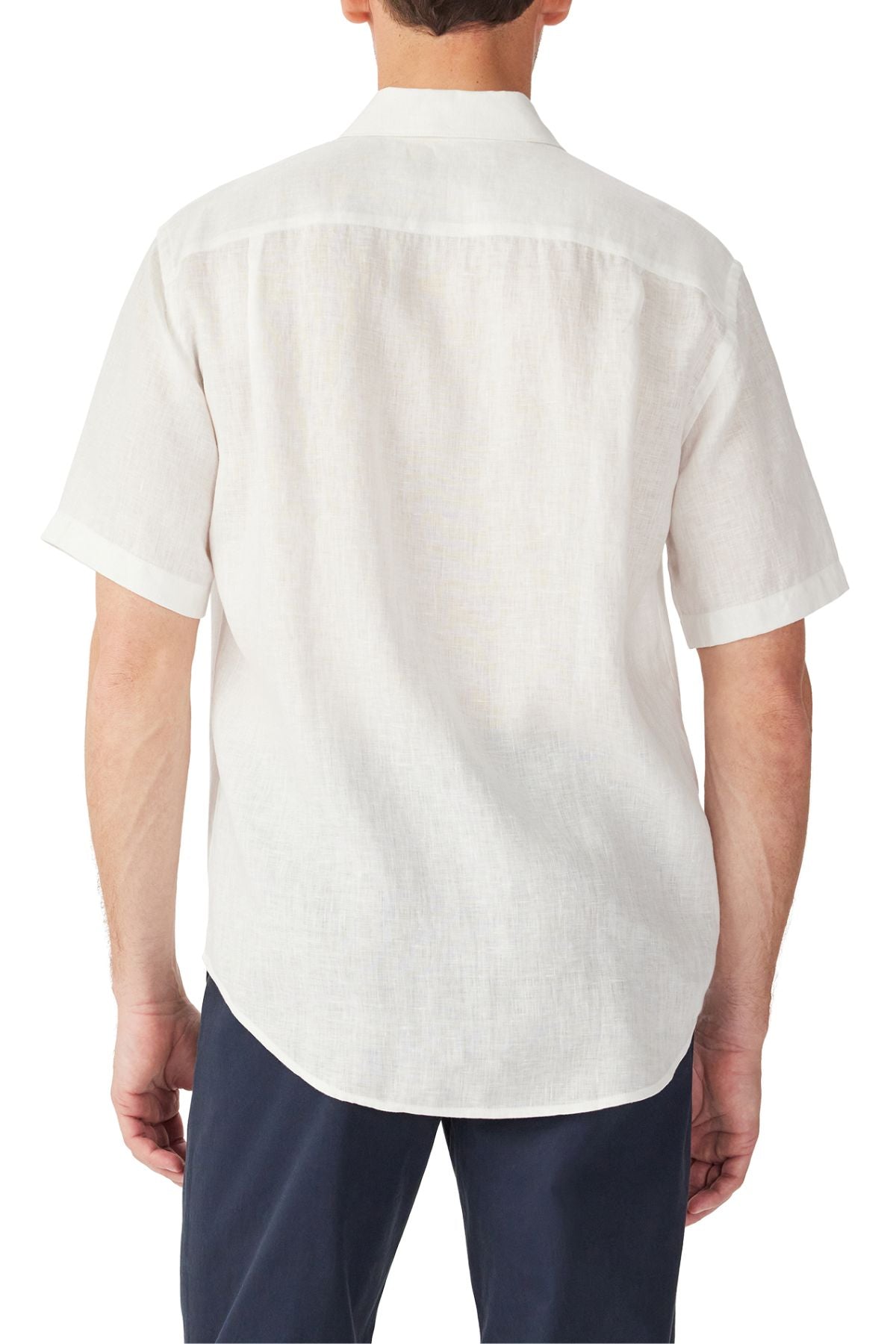 A man is seen from the back wearing the RM Williams Newman Linen Short Sleeve Shirt in white and dark pants. The relaxed, untucked fit adds a laid-back vibe against a plain white background.