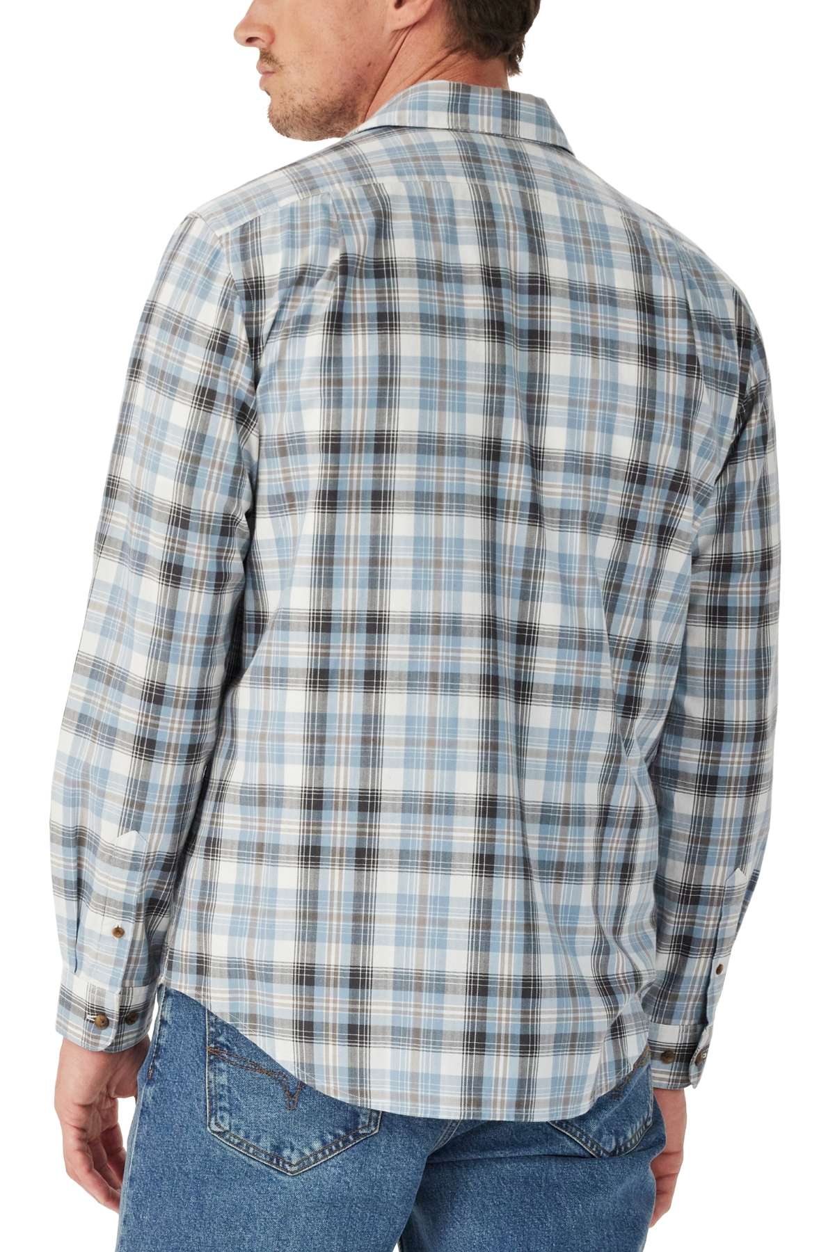 A man is shown from the back, looking over his shoulder to the left, wearing the RM Williams O'Connell Check Shirt—a long-sleeve light blue and gray plaid shirt—paired with blue jeans.