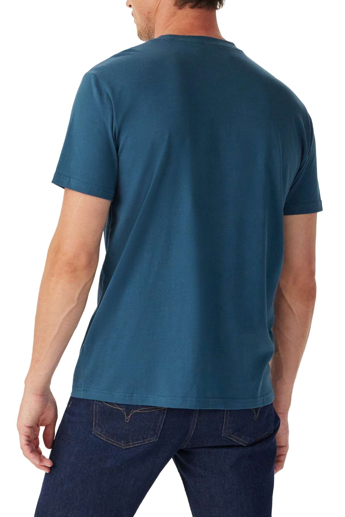 A man is seen from behind wearing a short-sleeved, teal RM Williams Parson T-Shirt and dark blue jeans against a white background.