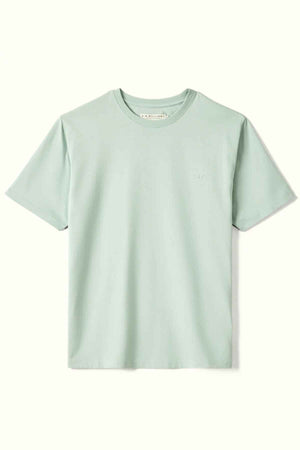 The RM Williams Parson T-Shirt, featuring a subtle logo on the left chest area, is displayed against a plain background. It is a light green crew neck shirt made from organic cotton and has short sleeves.