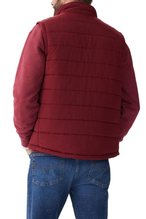 A person wearing an RM Williams Patterson Creek Vest in red, which is water-resistant and quilted with horizontal stitching, over a red long-sleeved shirt and blue jeans, is seen from behind. Their hands are in their jeans pockets.