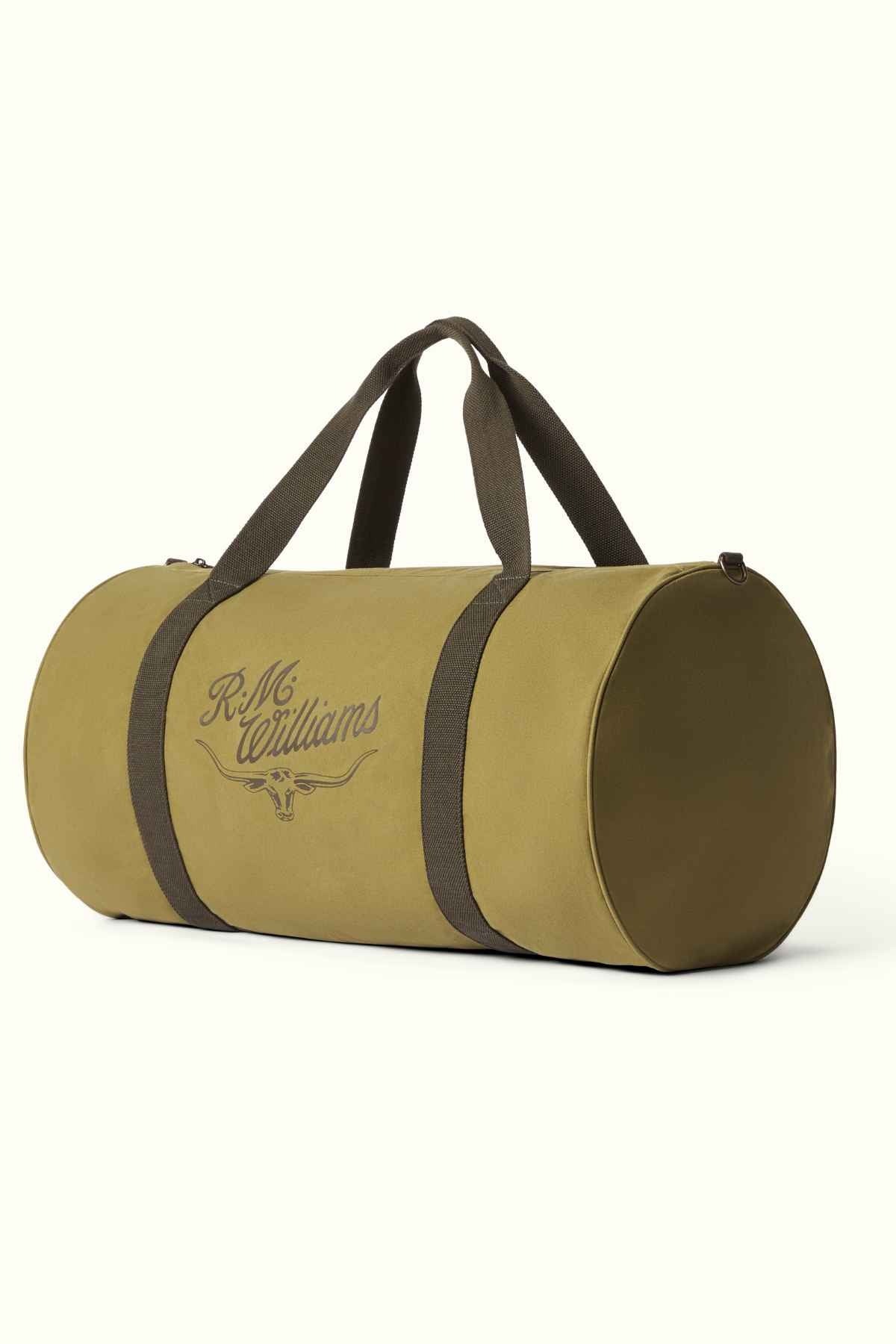 Introducing the RM Williams RM Ditty Bag: a green cylindrical duffel made from waxed cotton canvas, complemented by dark handles and a robust zipper. This ideal travel companion features "R.M. Williams" text and logo on the side, offering durability infused with Halley Stevensons' renowned craftsmanship.