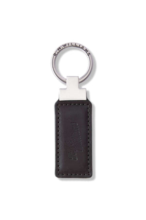The RM Williams Ridgewood Key Fob is a sleek, durable leather accessory featuring a metallic ring engraved with "R.M.Williams." It has a rectangular black leather fob with edge stitching and an embossed script logo, combining simplicity and elegance.