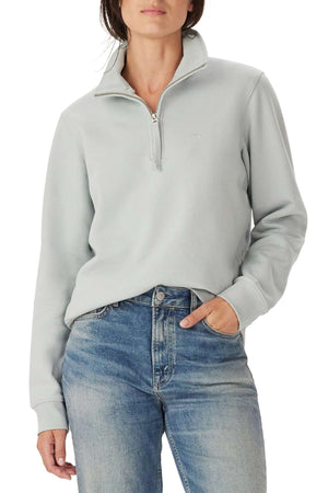 A person wears the RM Williams Trickett 1/4 Zip Sweatshirt in light gray with blue jeans, standing with one hand in their pocket against a plain background.
