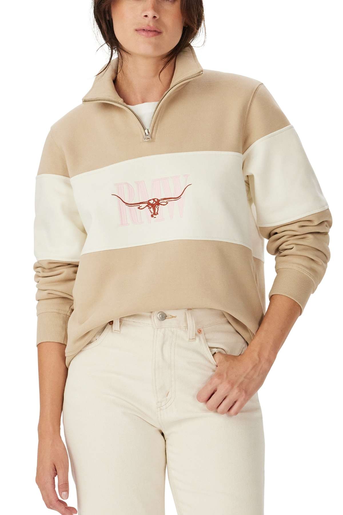 Someone wearing the RM Williams Trickett Panel Sweatshirt in beige and white with a longhorn graphic and "RAW" logo on the chest, styled with light-colored jeans.