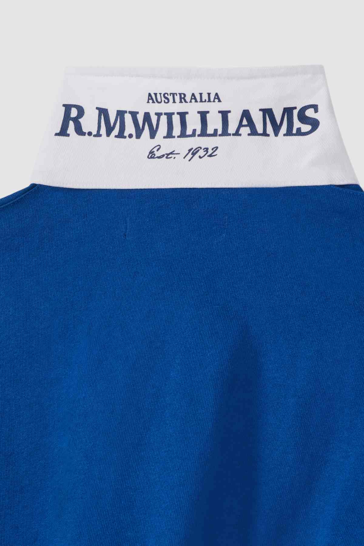 Close-up of the collar of the RM Williams Tweedale Rugby shirt, featuring a blue exterior with a white inside. The inner collar has "AUSTRALIA R.M. WILLIAMS Est. 1932" printed in dark blue text. The rest of the image prominently displays the heavyweight blue jersey fabric of the garment.