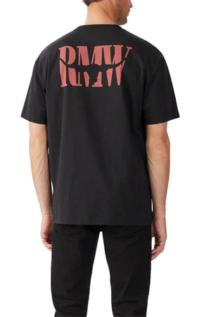 A man stands with his back to the camera, wearing a relaxed fit RM Williams Branded T-Shirt in black with bold red "RMV" lettering on the back and black pants, highlighting casual style in organic cotton jersey against a white background.