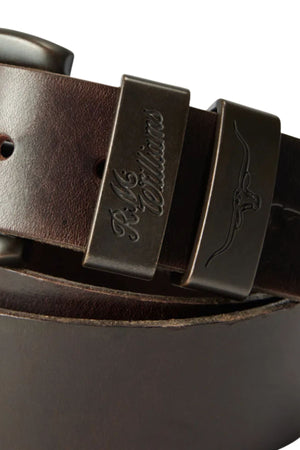 Close-up of the RM Williams Drover Belt, crafted in Australia from premium vegetable-tanned leather. Features a sturdy metal buckle engraved with "RM Williams" and an embossed longhorn logo.