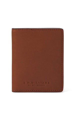 The RM Williams Farrier Fold Cardholder, crafted from full grain leather, stands upright with “R.M.Williams Est. 1932, Australia” embossed near the base. The white background accentuates its classic look and practical interior card slots.