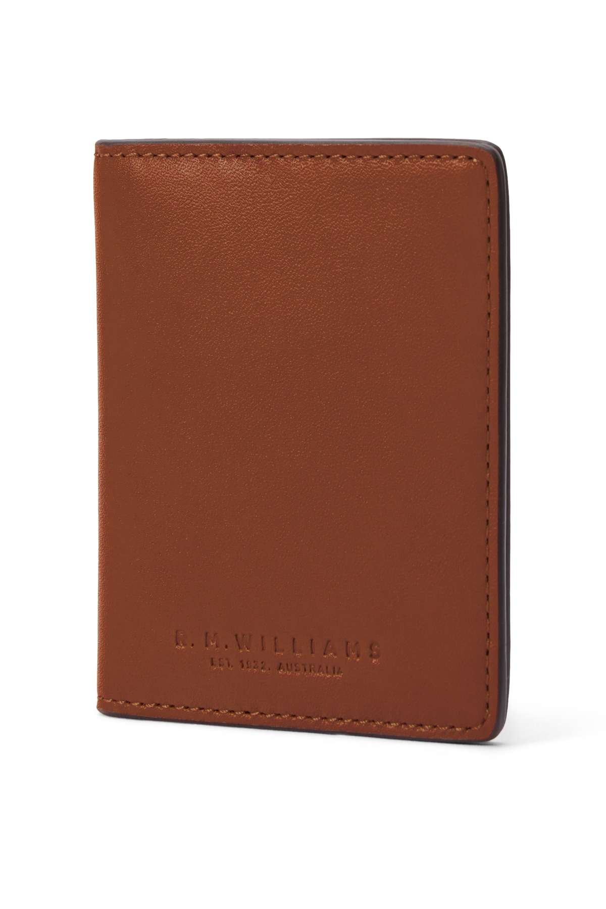 A brown RM Williams Farrier Fold Cardholder stands upright, showing embossed "R.M. WILLIAMS EST. 1932 AUSTRALIA." text. It features clean stitching and multiple card slots for a simple, classic look.