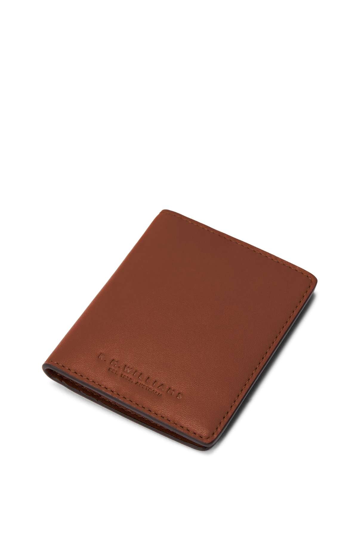 The RM Williams Farrier Fold Cardholder is a slim, brown full grain leather wallet with visible stitching, shown closed at a slight angle on a white background. The embossed R.M.Williams logo appears near the bottom left corner.
