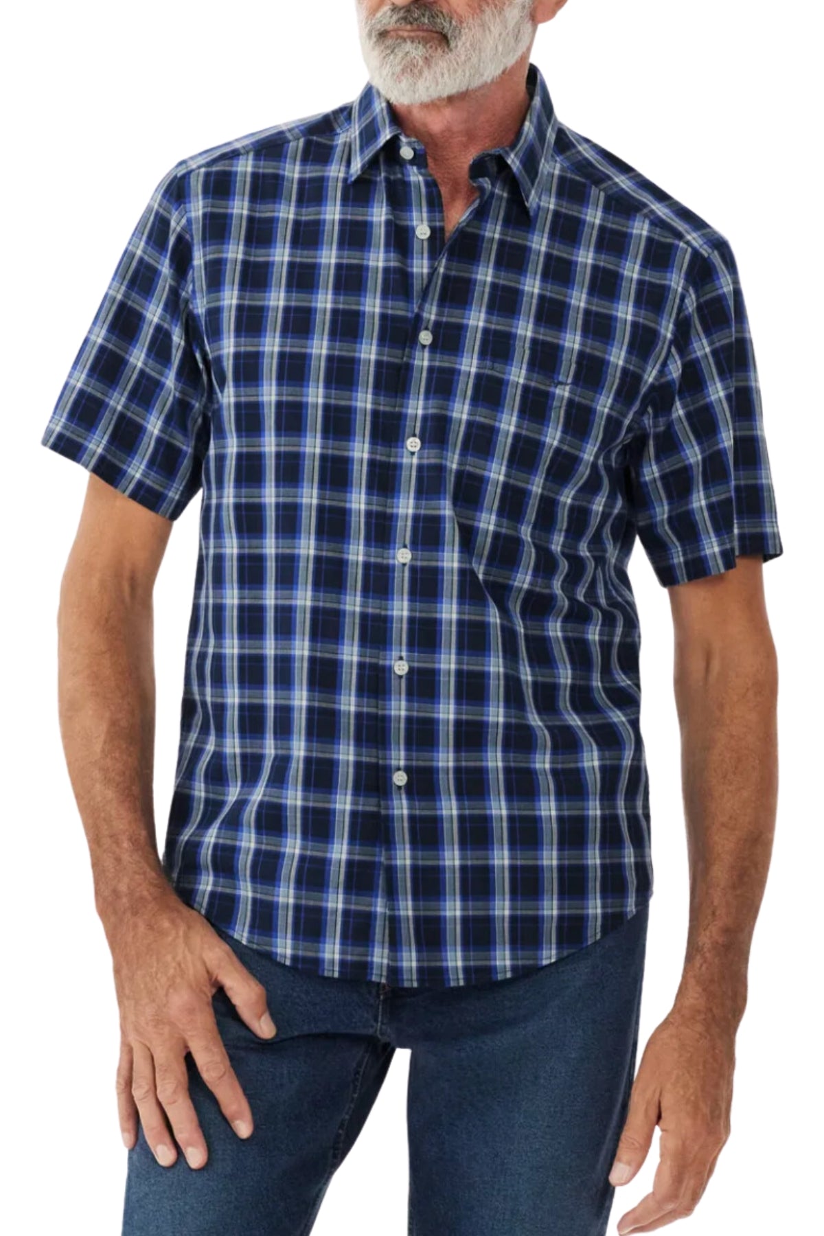 A person is wearing the RM Williams Hervey Shirt, a short-sleeve, button-up shirt featuring a blue and black plaid pattern. The breathable cotton fabric drapes comfortably over their frame, showing a relaxed silhouette. They have a white beard and are also wearing blue jeans. The background is plain white.