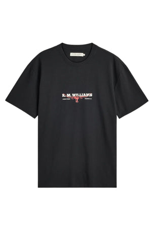 The RM Williams Holt Tee is a black, relaxed fit t-shirt crafted from Australian cotton, showcasing “R.M. WILLIAMS” text and a small bull logo in white and red as a branded chest print. The tee is displayed against a white background.