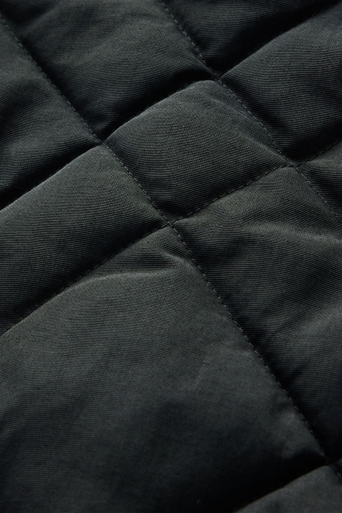 Close-up of the RM Williams Ikara Vest in black, highlighting its quilted fabric with square stitching patterns and a soft, padded texture.
