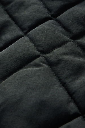 Close-up of the RM Williams Ikara Vest in black, highlighting its quilted fabric with square stitching patterns and a soft, padded texture.