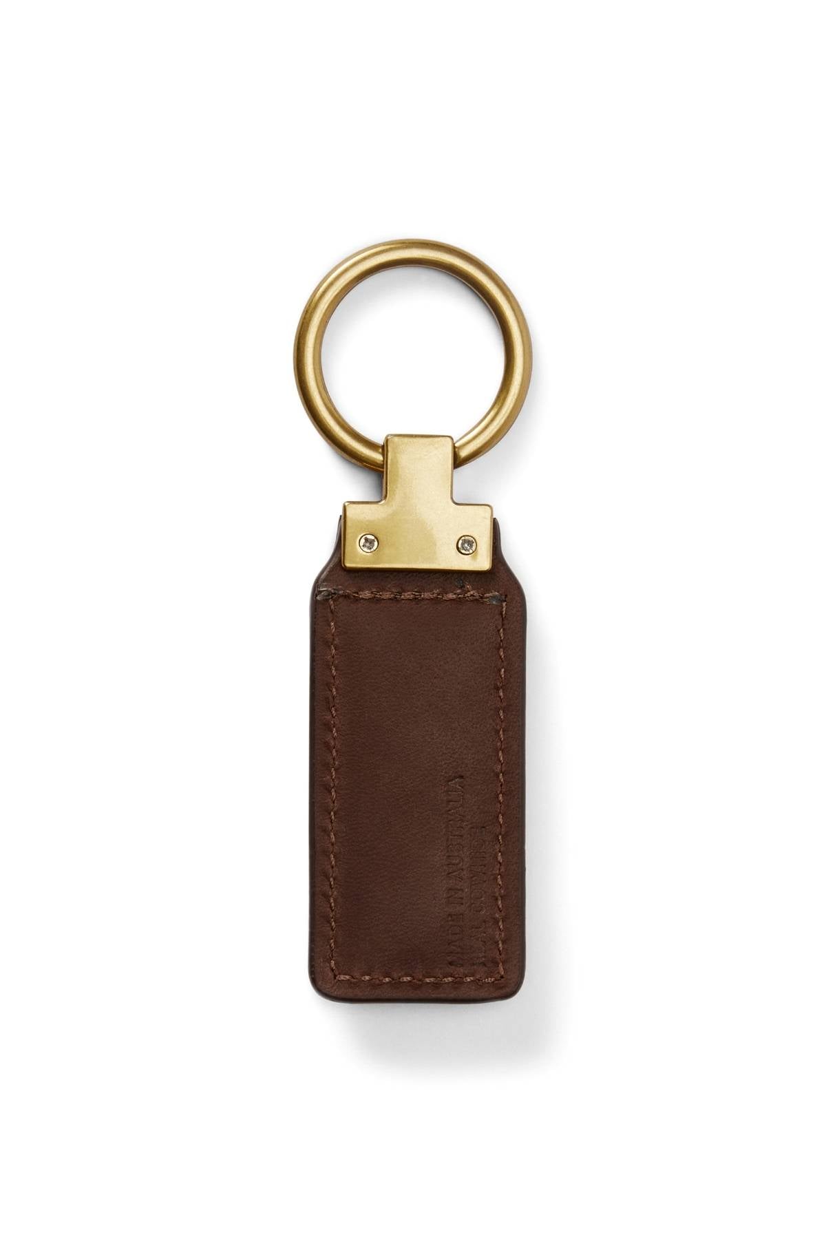 The RM Williams Angaston Key Fob is a brown leather keychain with a rectangular tag, featuring visible stitching, a large split keyring, and metallic detailing where the ring attaches to the leather.